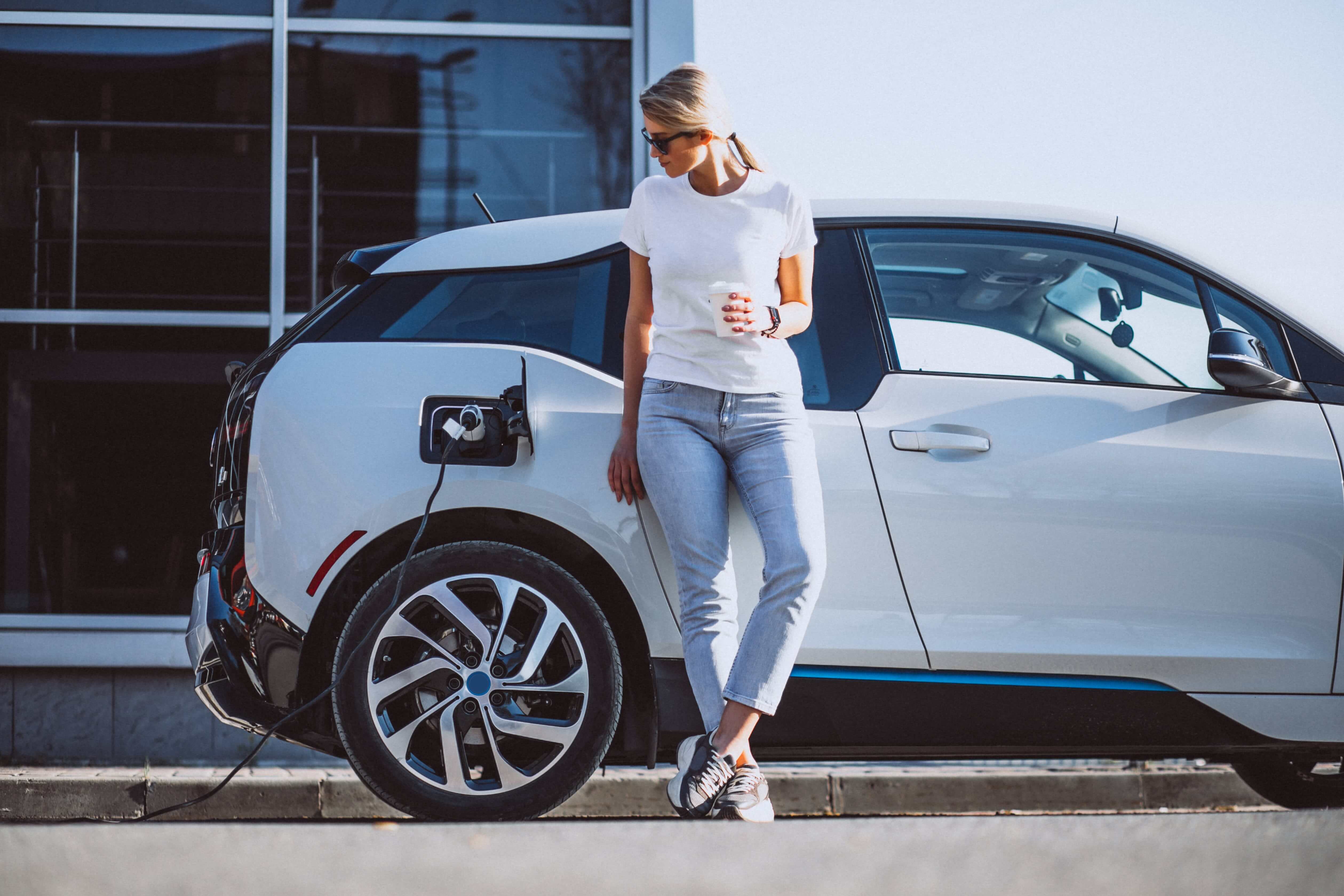 Woman with coffee in hand next to a charging car